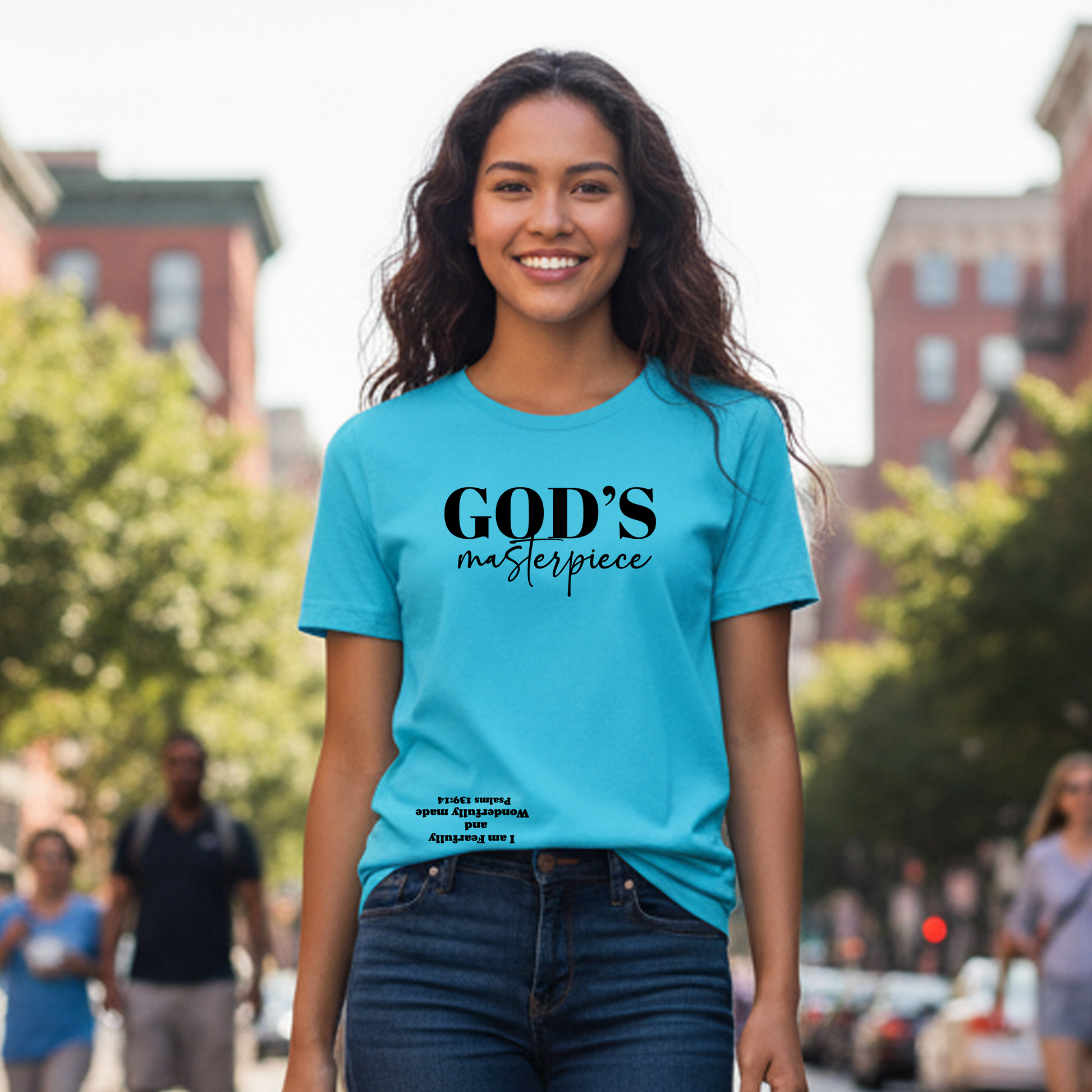 Woman wearing a blue t-shirt with 'GOD'S masterpiece' text on a city street.