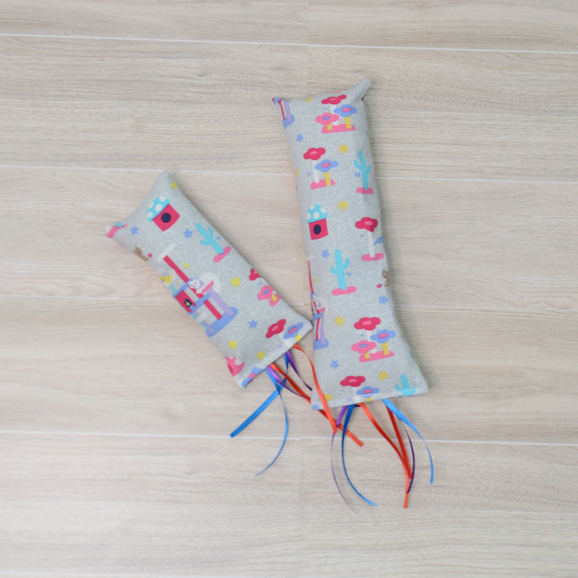 Two Kitty Kicker toy with  cat design and colorful ribbon on a wooden surface