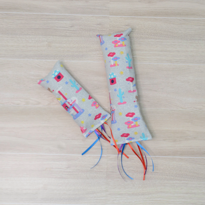 Two Kitty Kicker toy with  cat design and colorful ribbon on a wooden surface