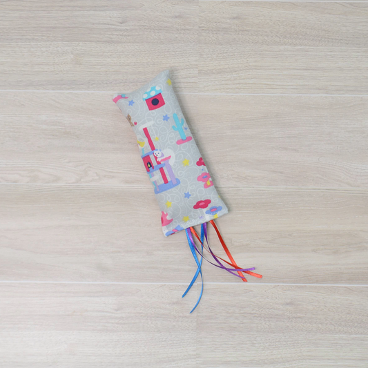 Kitty Kicker toy with  cat design and colorful ribbon on a wooden surface