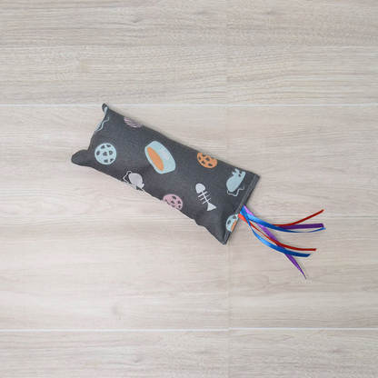Gray Kitty Kicker toy with mouse and fish  design and colorful ribbon on a wooden surface